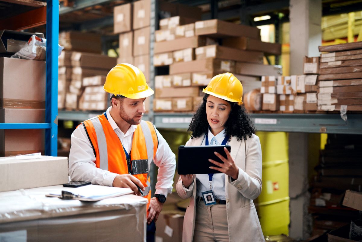colleagues working together over tablet checking paperwork in warehouse