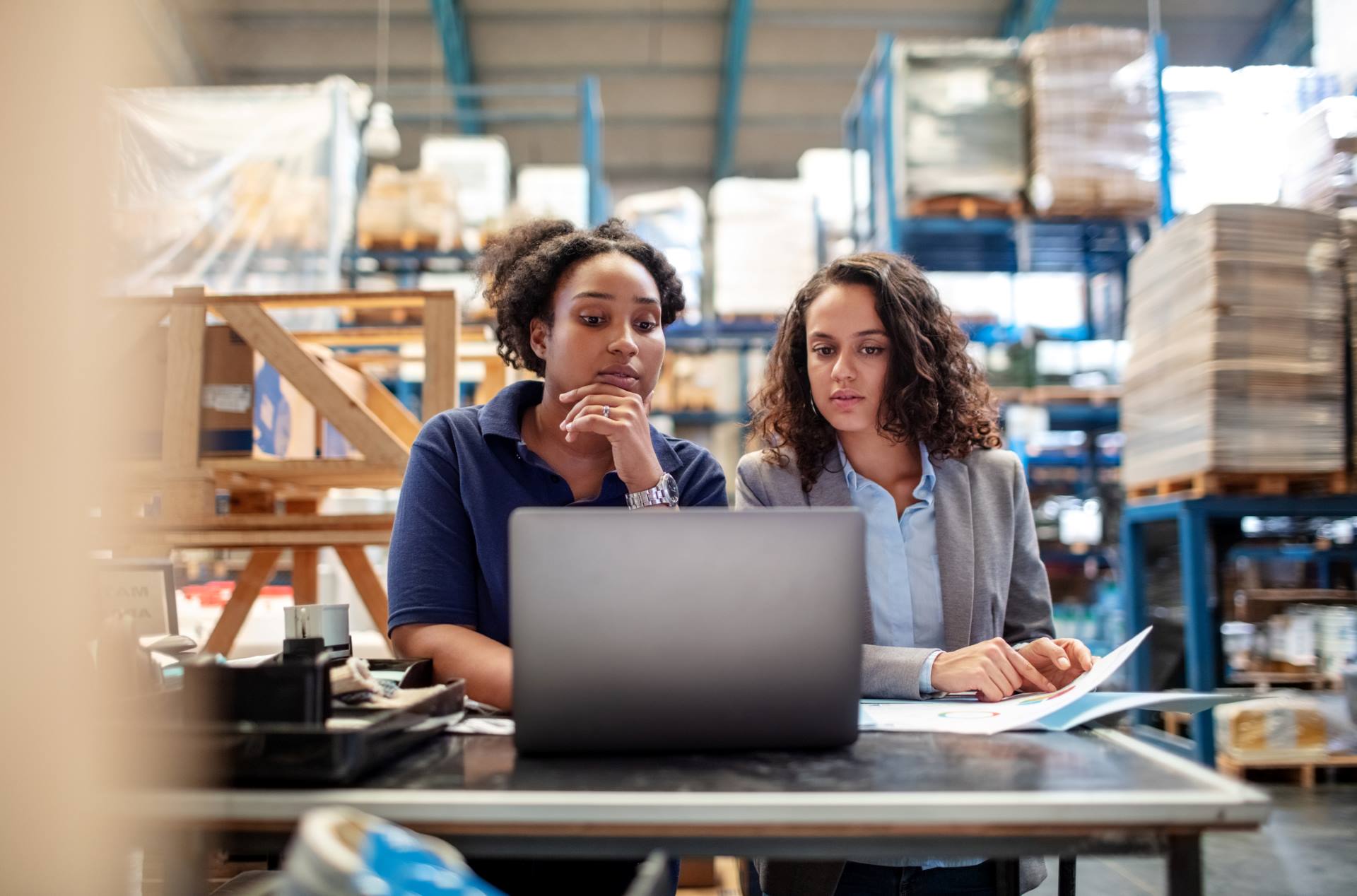 Colleagues in warehouse review paperwork for shipping overseas